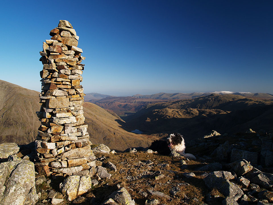 The slender columnar cairn on Lingmell. A clear view to the east with Helvellyn dusted with snow. 